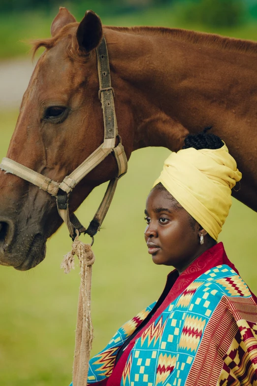 a beautiful young woman in native clothing standing next to a horse