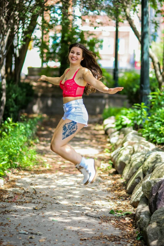 a woman in blue shorts jumping on a path