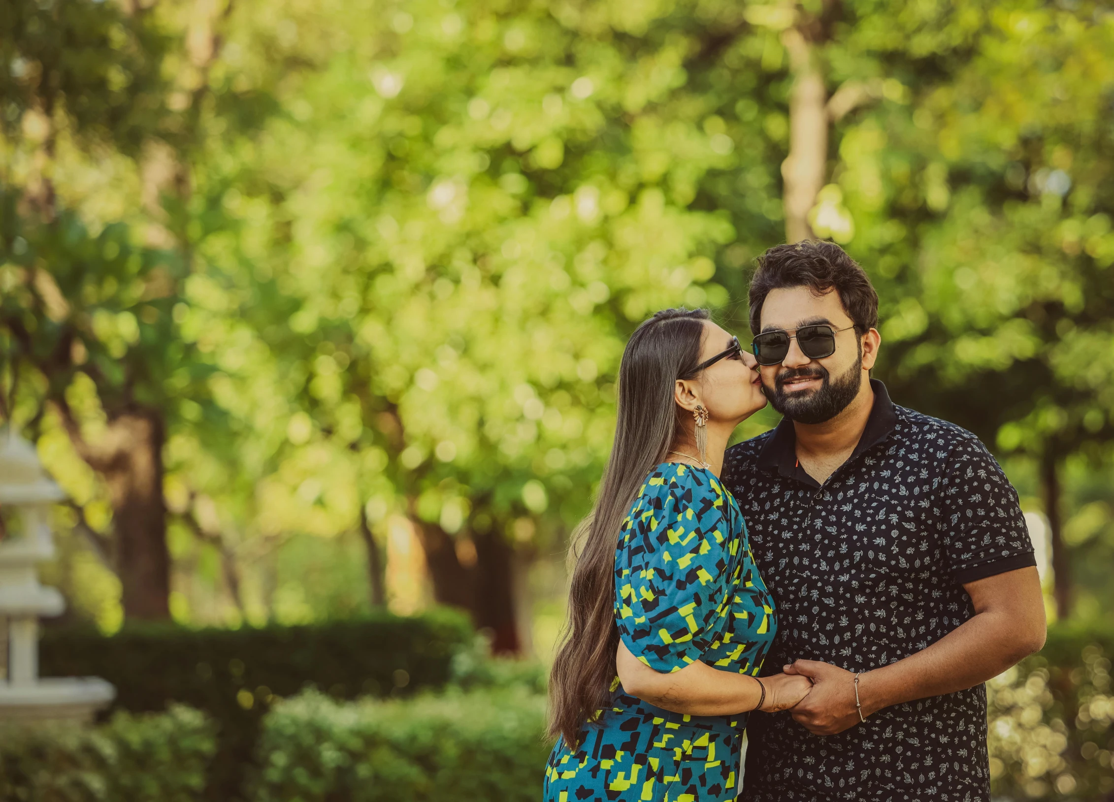 a couple kissing each other in front of some trees