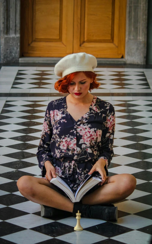 a lady wearing a hat sitting on a tile floor