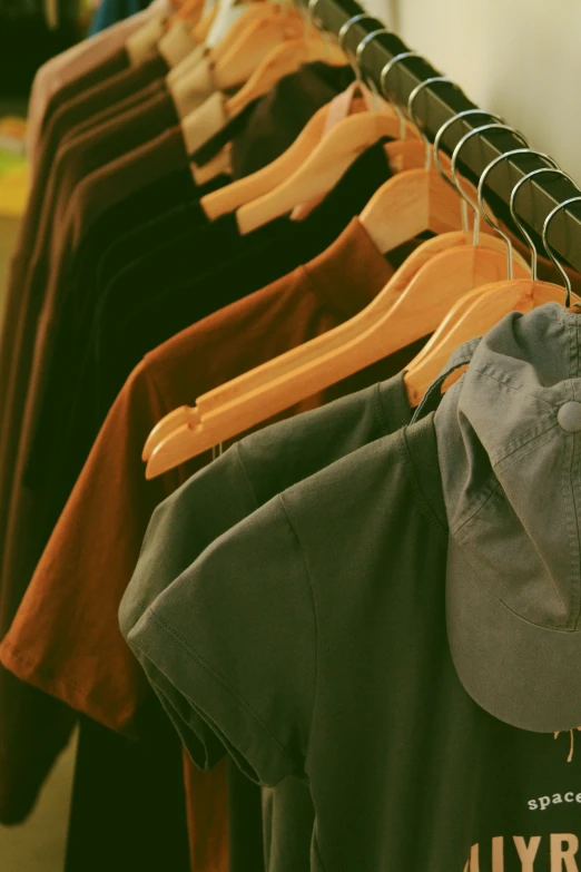 a row of clothes on wooden hangers with shirts hanging on the line