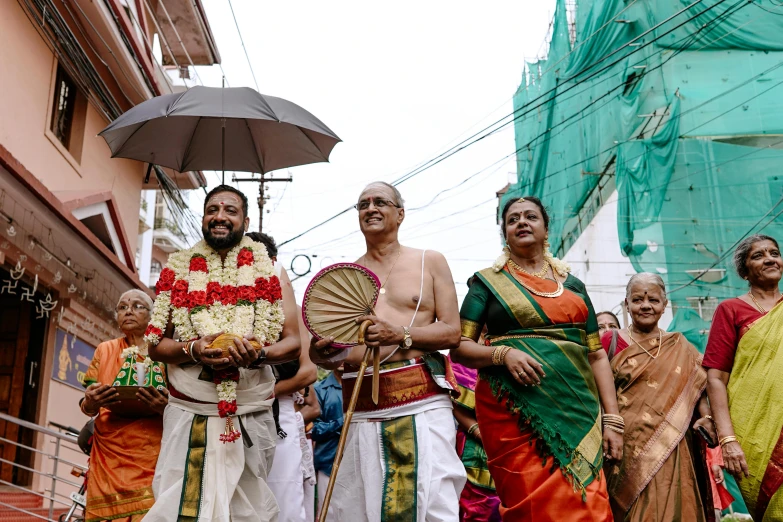 several people in traditional attire standing with an umbrella