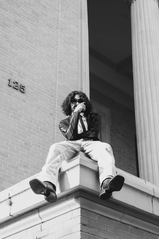 a man sitting on top of a white building with a phone