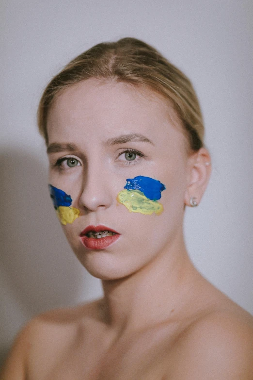 a beautiful blonde woman with blue and yellow painted on her face