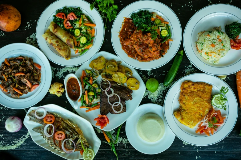 a large selection of food served on white plates