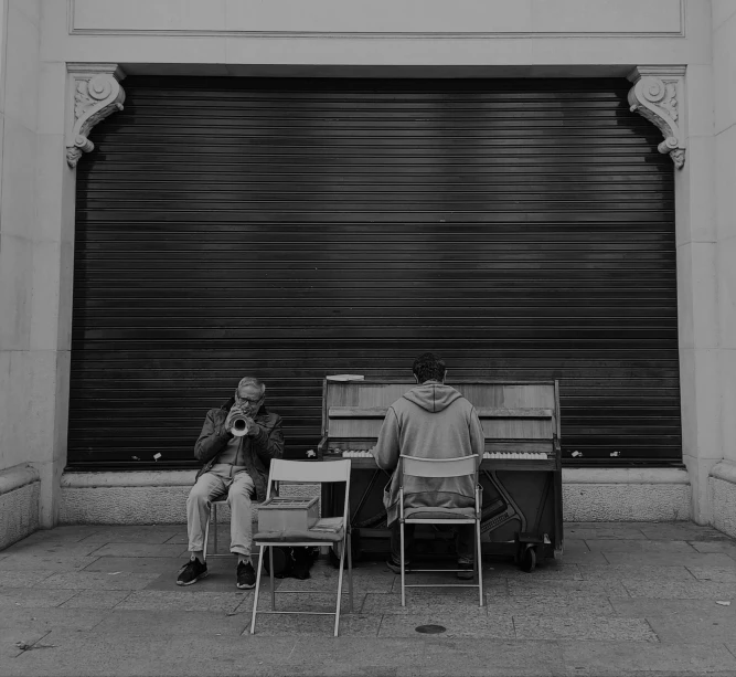 two people sitting on benches in front of a closed garage door