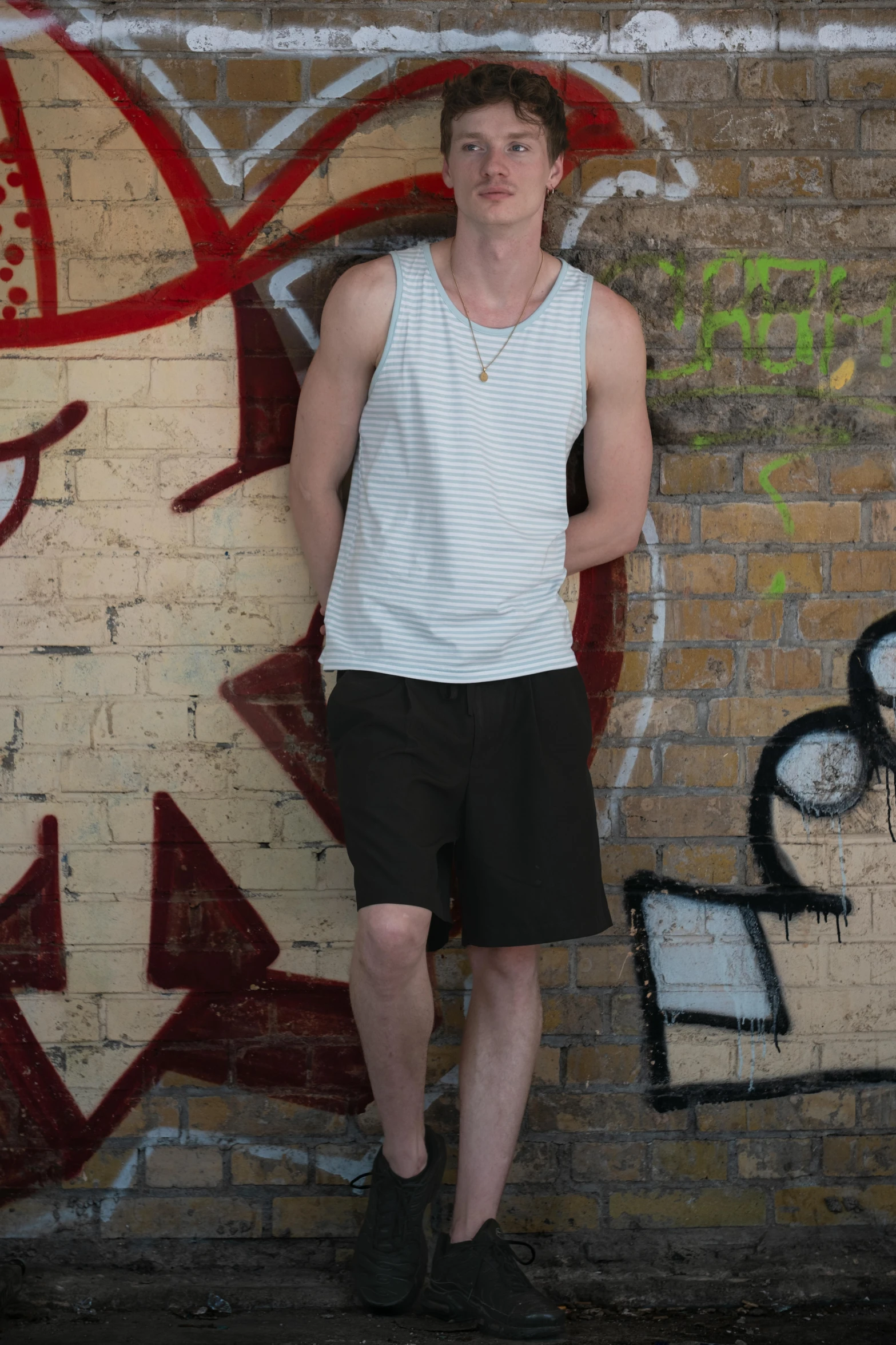 a man standing against graffiti wall next to his pants