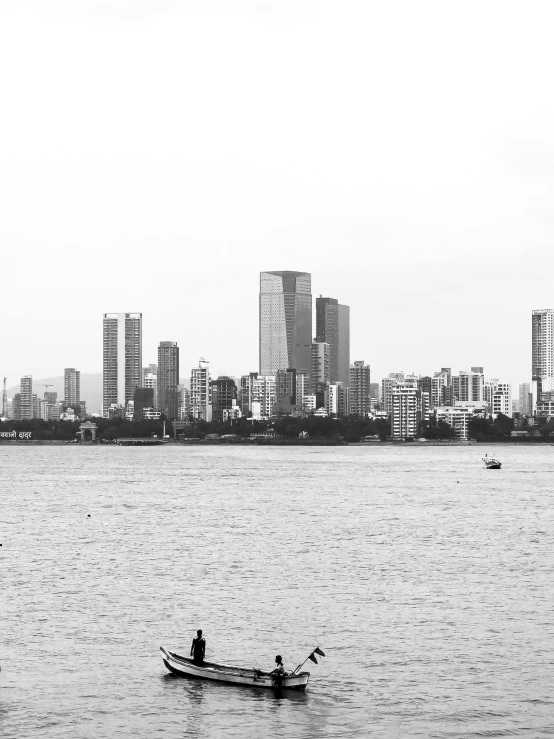 black and white image of a man in a boat near a city