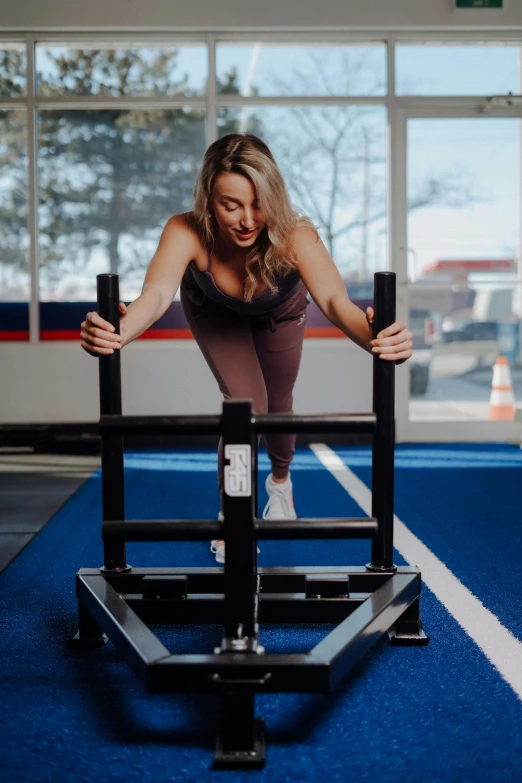 a woman is in a gym holding two dumbbells