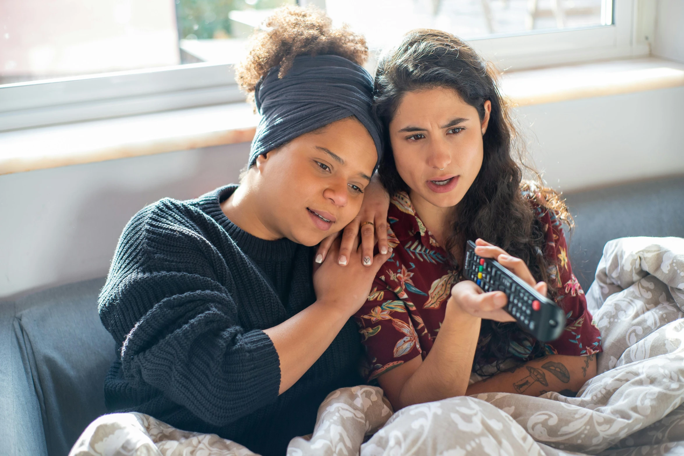 the woman is holding a remote and looking at her cell phone