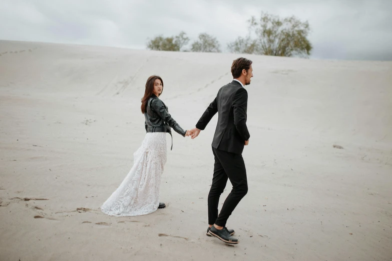 a newly married couple walk through the sand