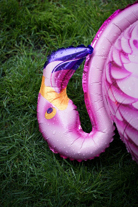 this is a pink flamingo air filled balloon sitting on the grass