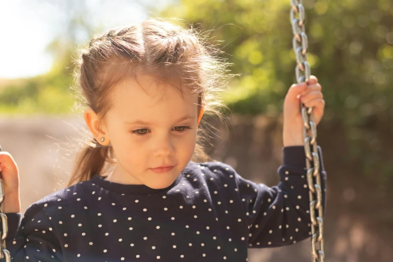 a little girl playing with a swing set