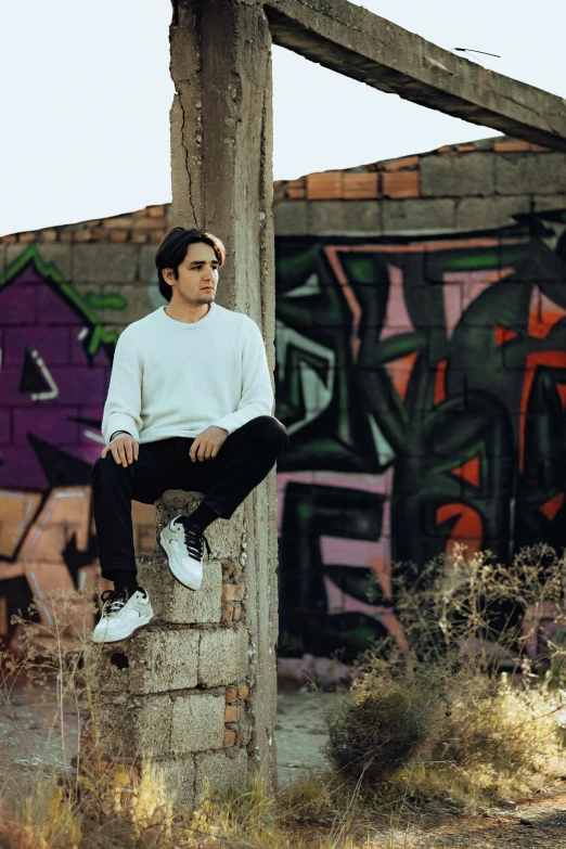 a young man is sitting on the edge of a brick structure