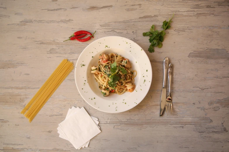 a plate with pasta next to a fork and spoon