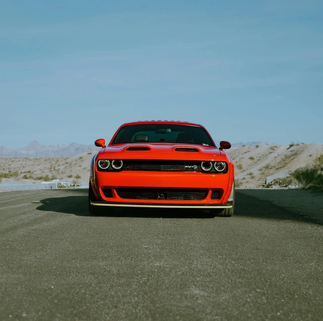 the bright orange sports car is parked in the desert