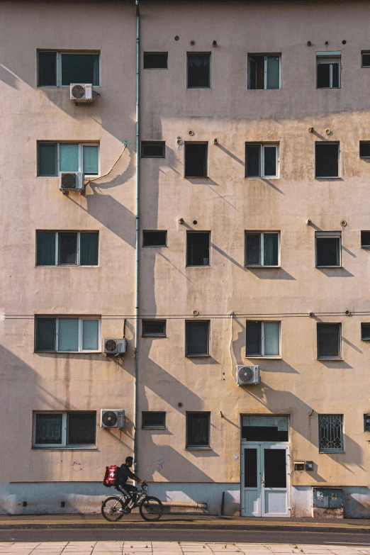 a man rides a bike past some buldings in an industrial area