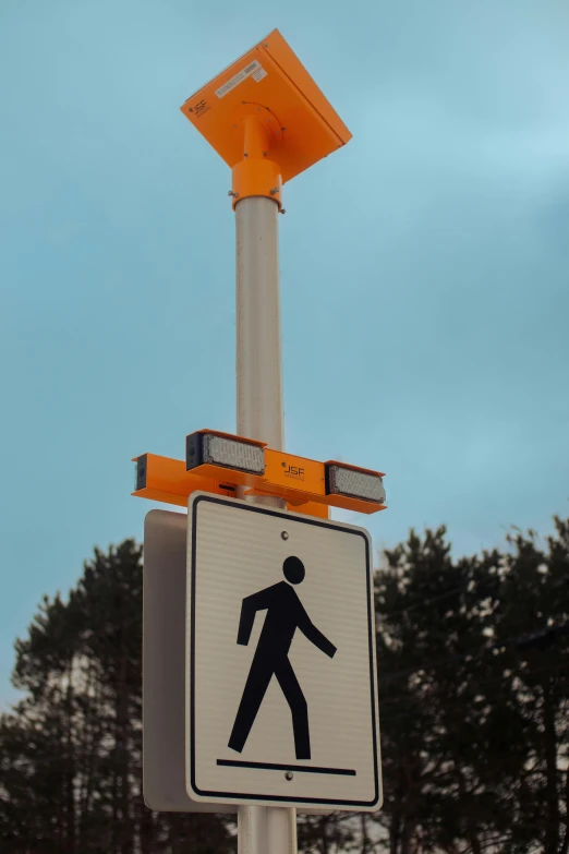 a pedestrian crossing sign with an orange traffic signal