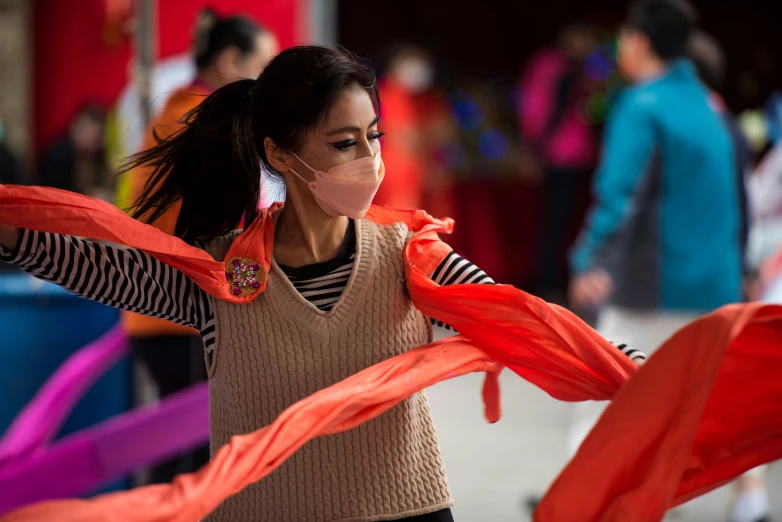 a woman is holding a red scarf while walking