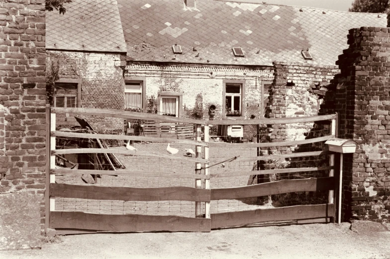 this is a sepia po of an old barn with the gate partially open