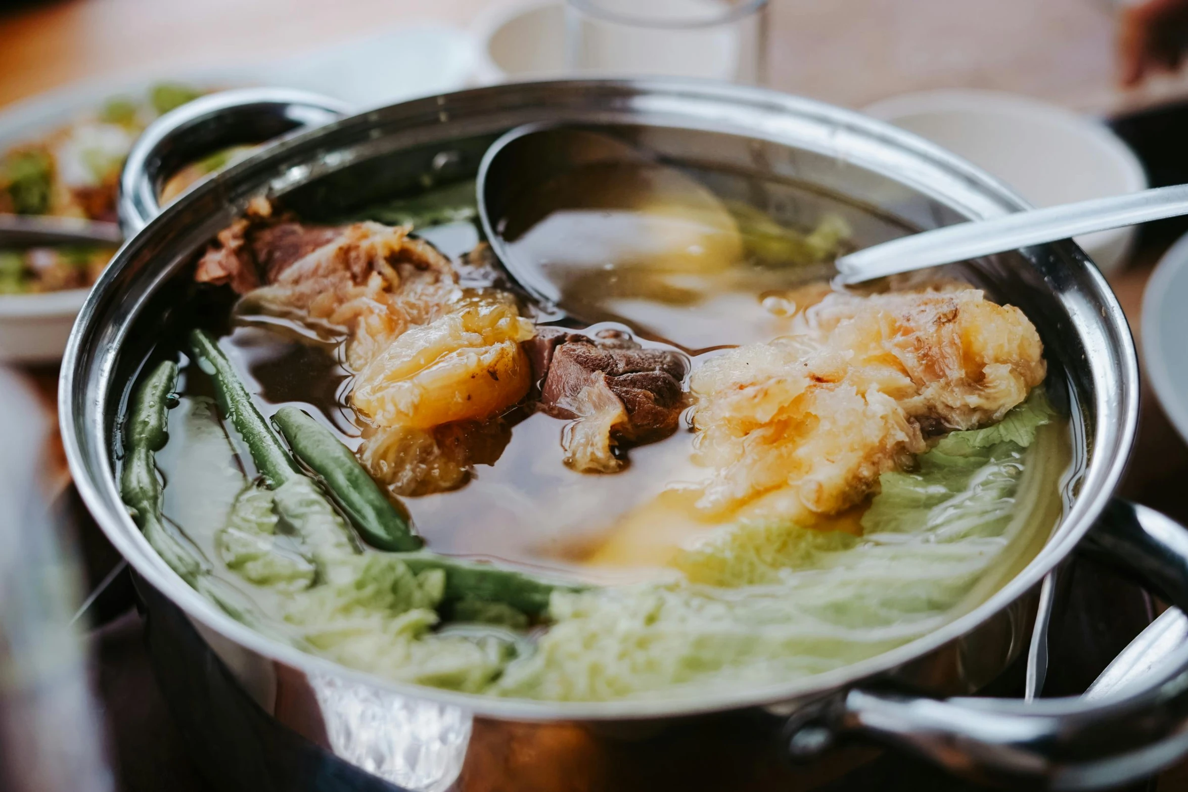 the metal bowl with the soup in it is filled with meat