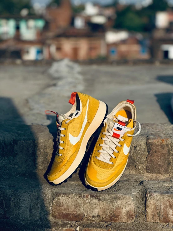 yellow nike sneakers sitting on concrete ledge above urban area