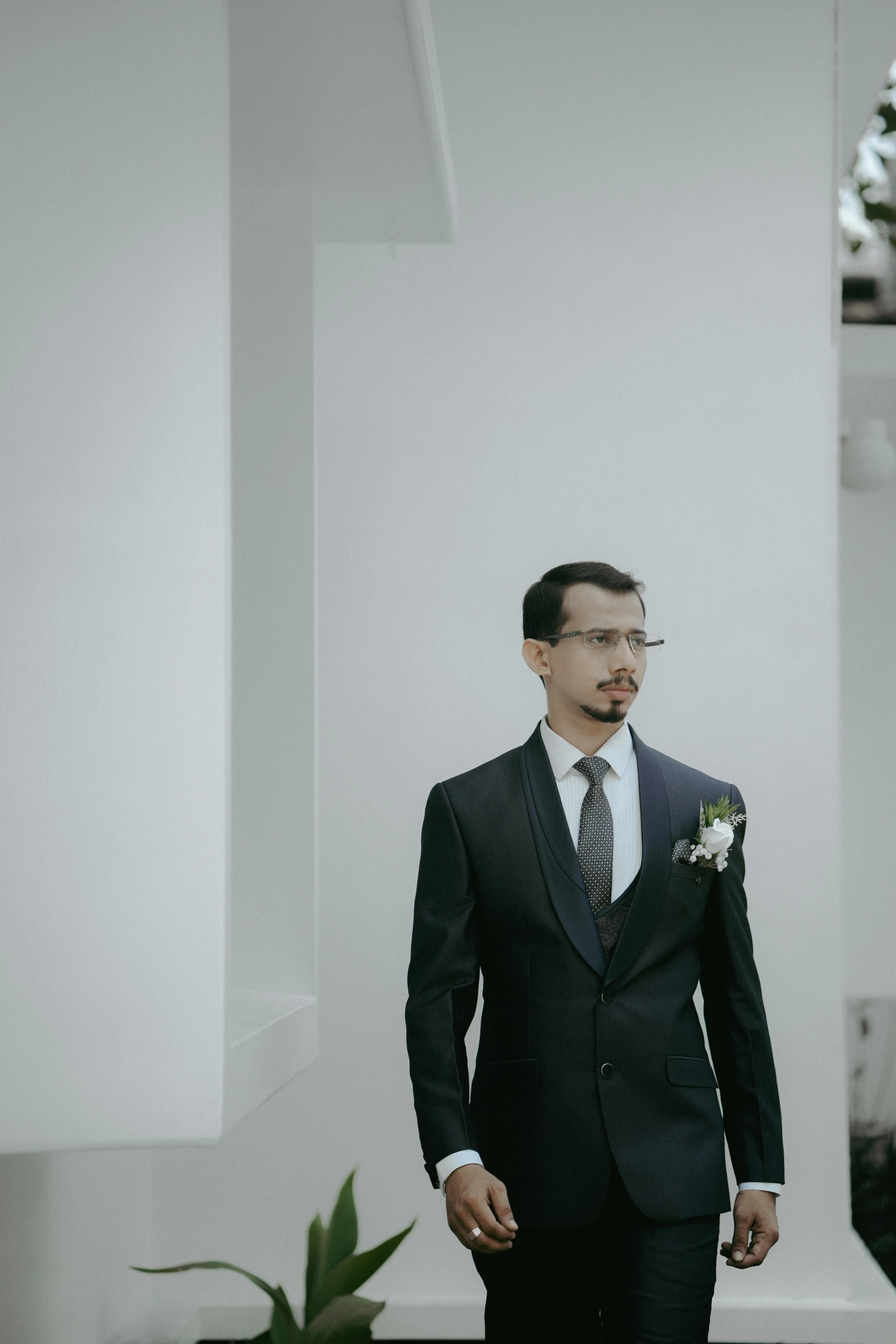 man standing in a room holding a flower and wearing a suit