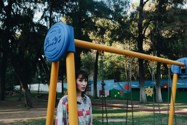 a woman standing on a playground with swing set