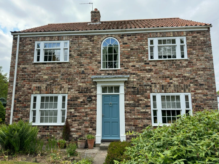 a brick building has two blue windows and a green plant