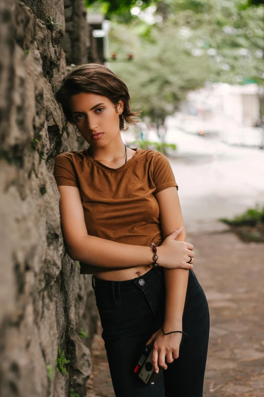 a girl is leaning on a stone wall and looking straight ahead