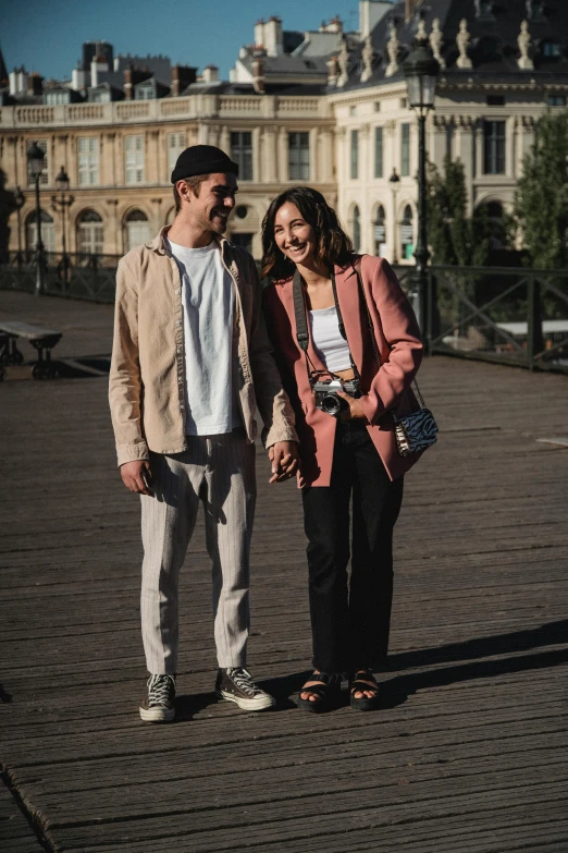 two people standing on the side of a road near a building