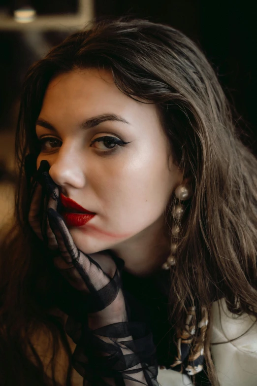 a woman with red lips in white coat and sheer black scarf