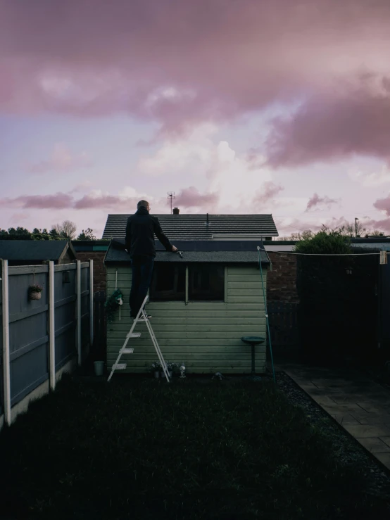 man on a ladder in front of a white fence