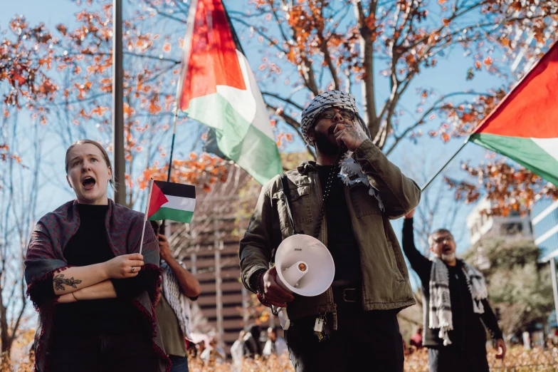 two men are talking into the microphone while protesting with flags