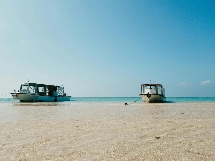 two boats sitting on top of a beach next to the ocean