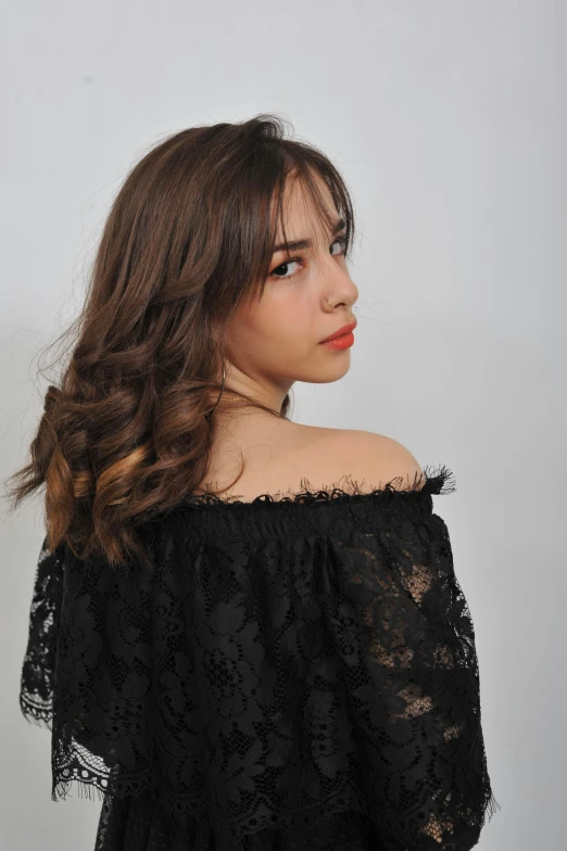 a woman with wavy hair wearing black off the shoulder top