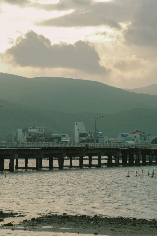 a pier with mountains and clouds in the background