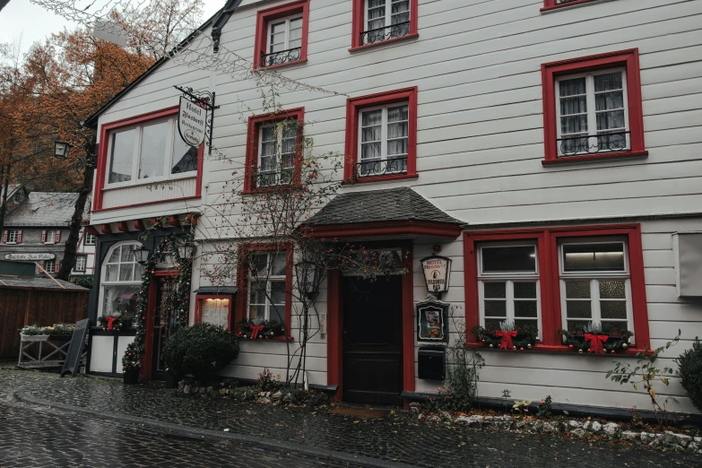 a large white house with red windows and wreaths