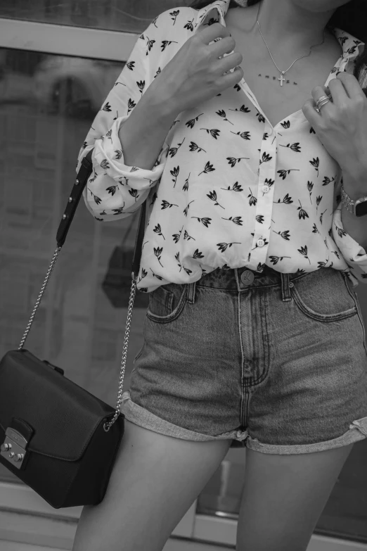 a girl wearing an ornate blouse and shorts holding onto a bag