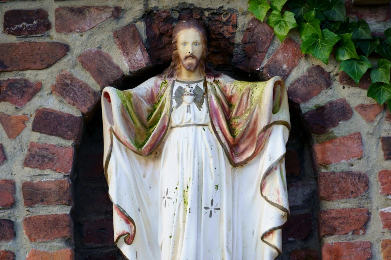 the statue of jesus christ appears to be standing against a brick wall