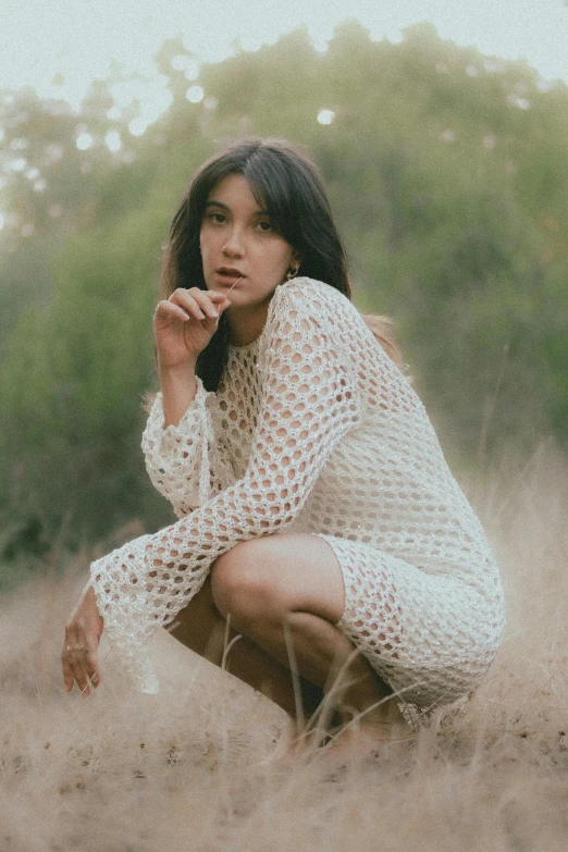 a woman sits in a field of dry grass