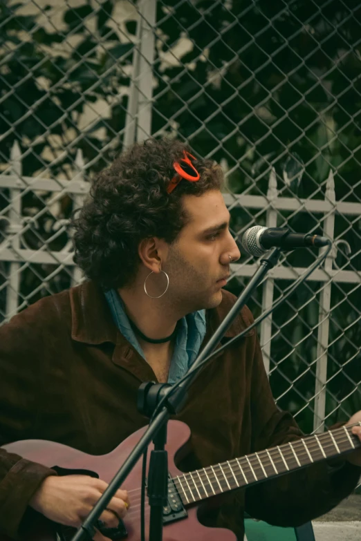 man playing a guitar and singing into a microphone