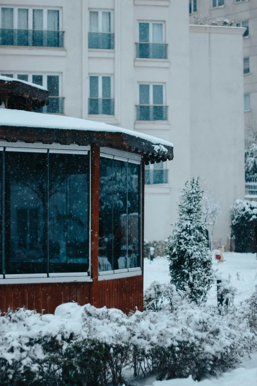 snow falling on the ground next to a building