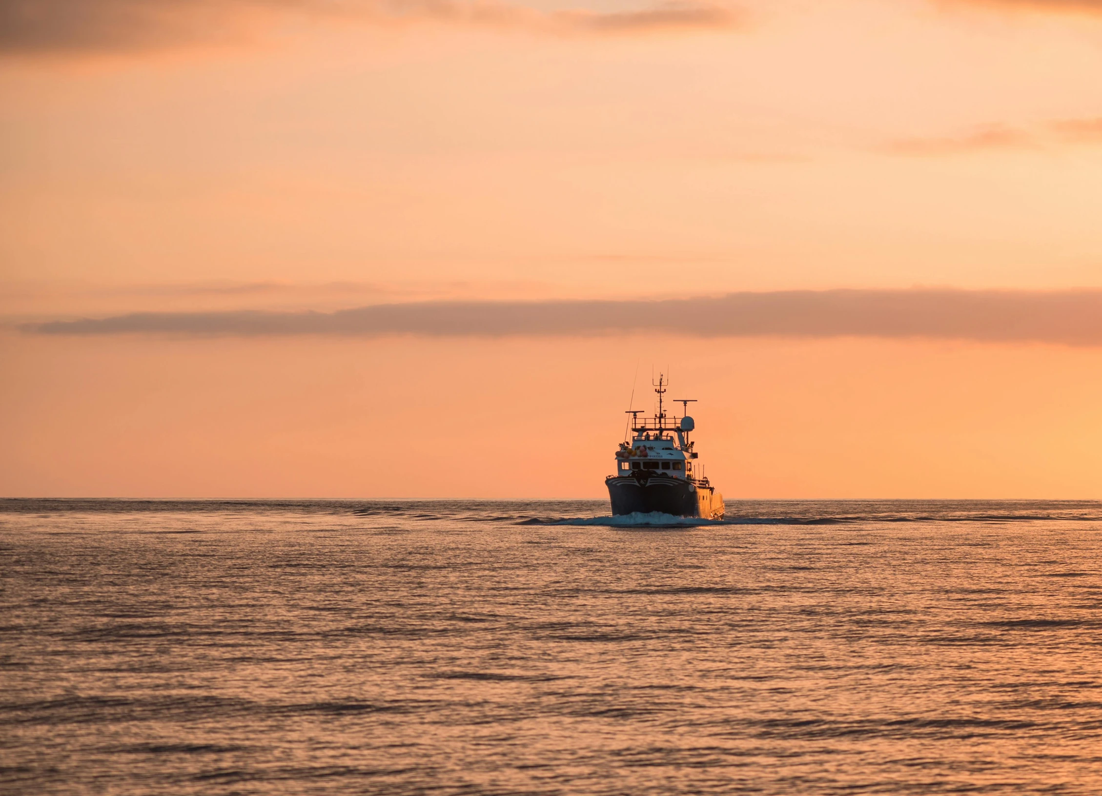 a boat sailing on the ocean in front of a sunset