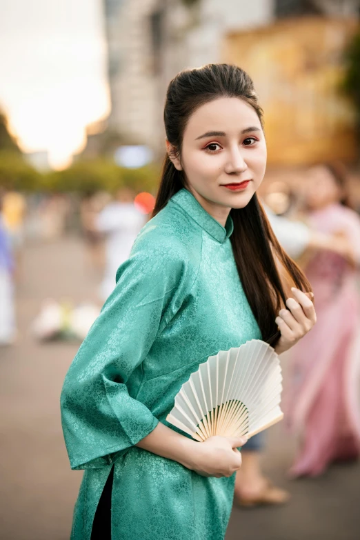 a woman in a long sleeved dress poses with her paper fan