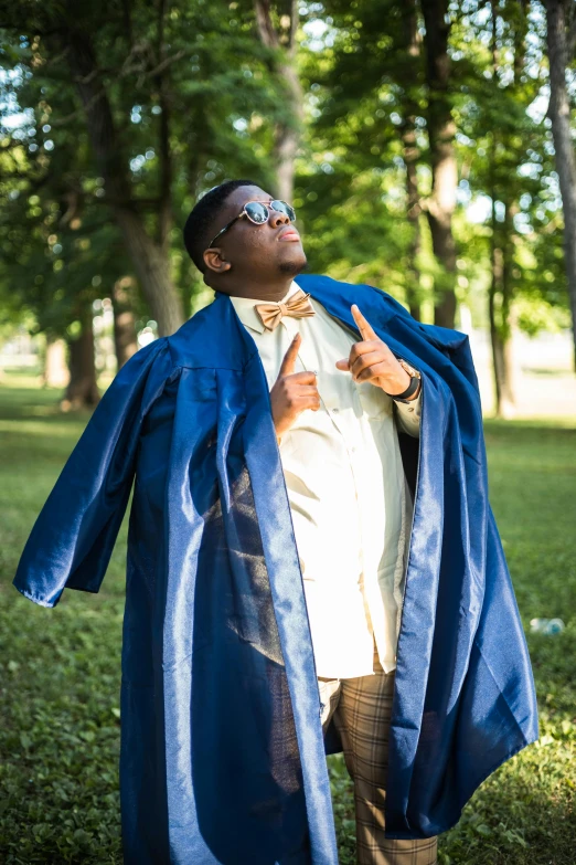 a black man in a blue robe is standing on the grass