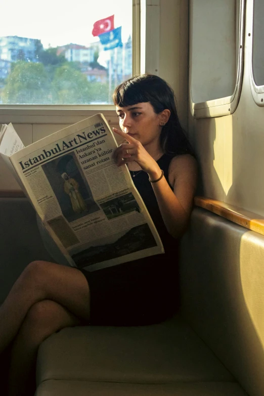 a woman sits on a train reading a newspaper