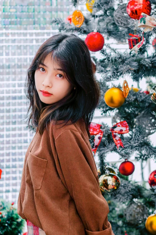 a young woman standing in front of a christmas tree