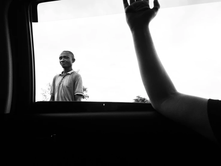 a man holding up his hand out the window of a bus