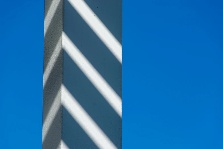 shadows against a blue sky and a tall building